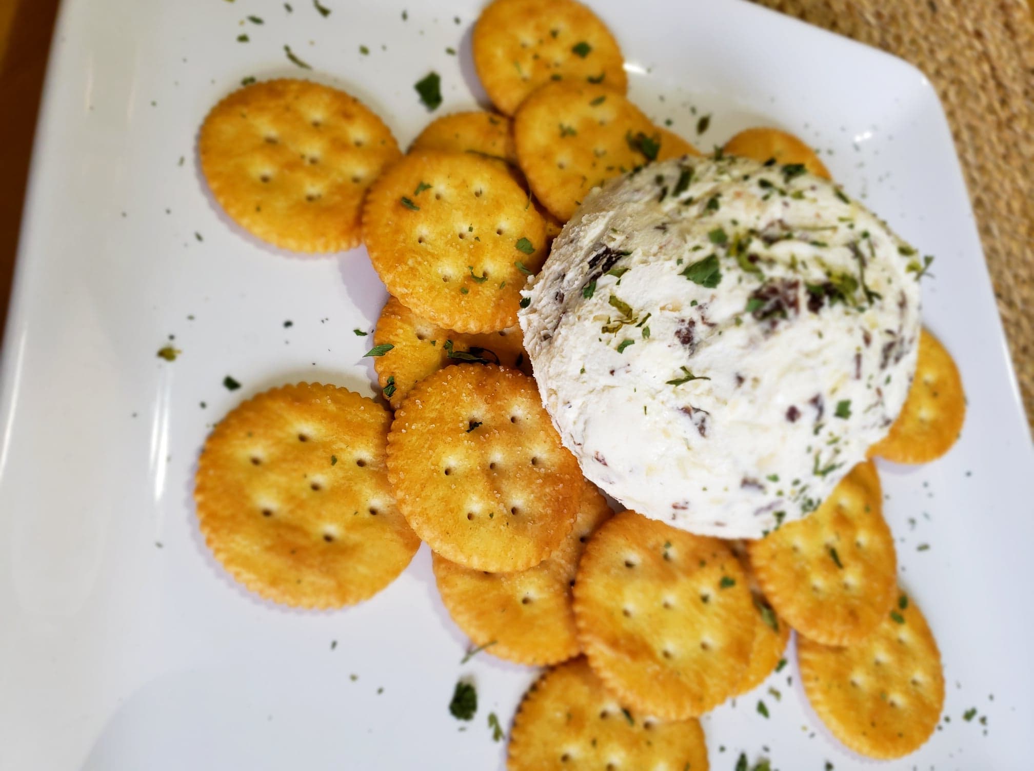 A cheese ball on top of crackers on a white plate