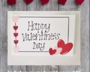 Happy Valentine's Day gift note on wood background with hearts pinned to a string by clothes pins and the words include a message with your gift