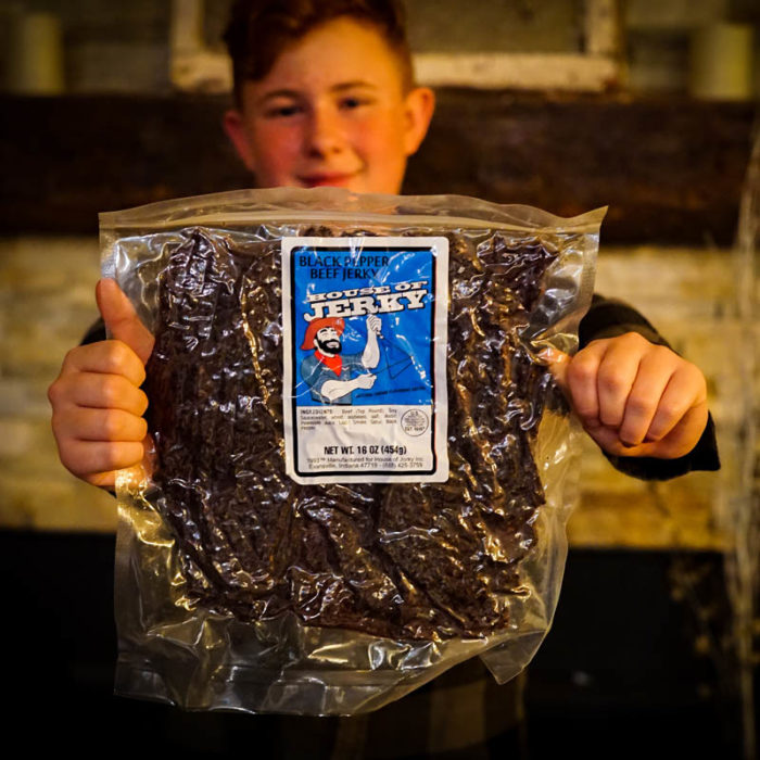 Boy holding 1lb bag of jerky in front of fire place